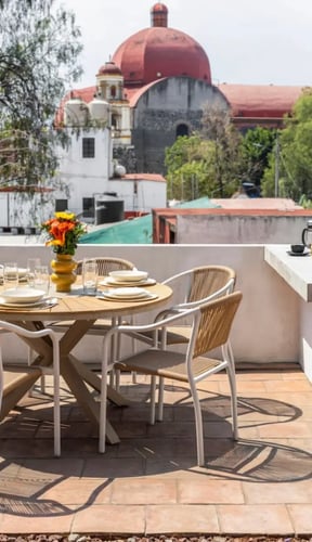 Rooftop terrace with a round dining table and BBQ overlooking a colonial church with a red dome